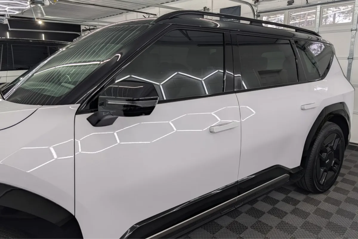 A close-up of a white SUV with black accents and tinted windows in a clean garage