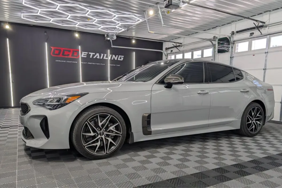 White Kia Stinger protected with ceramic coating in a detailing garage.