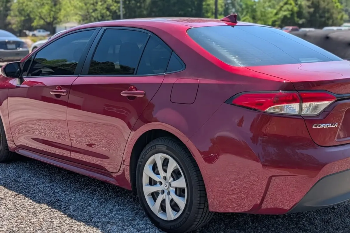 Rear side view of a red Toyota Corolla with dark window tint.