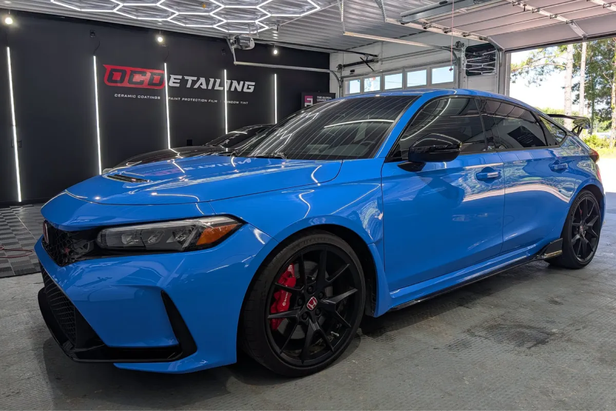 Blue Honda Civic with freshly cleaned tinted windows in a detailing shop.