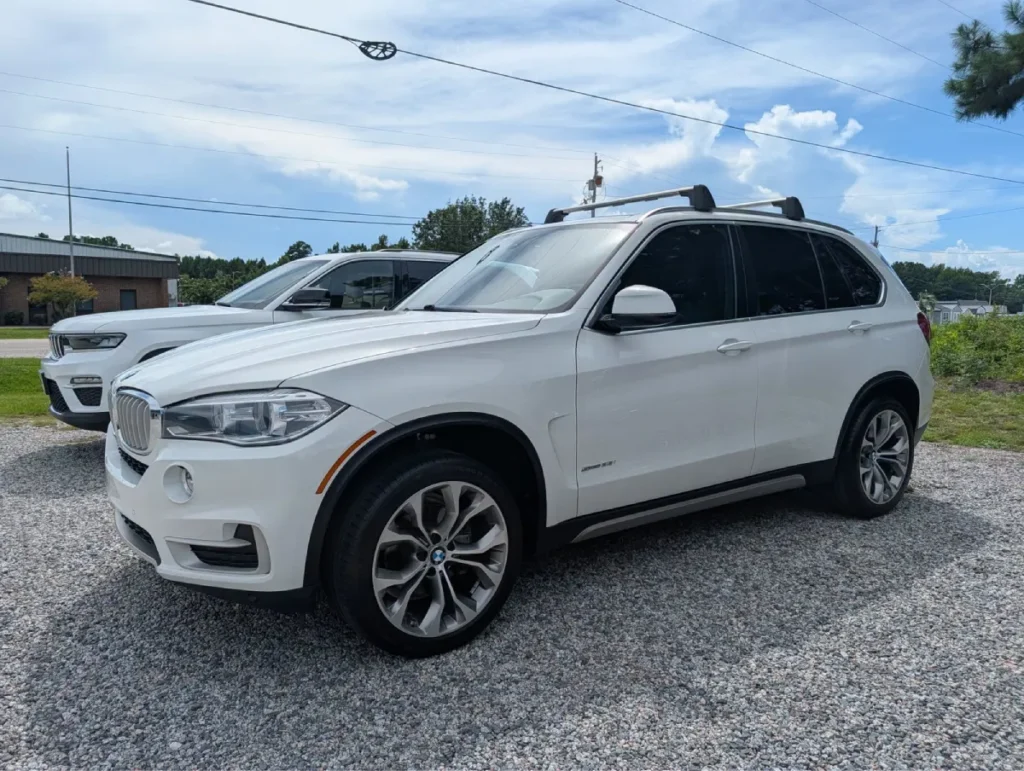 White BMW SUV with dark window tinting parked outdoors on gravel