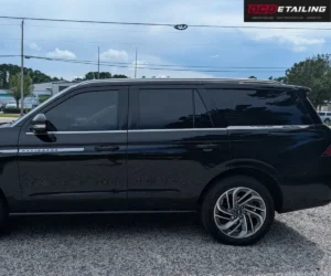 Close-up side view highlighting the dark tinted side windows and alloy wheels of a black Lincoln Navigator.